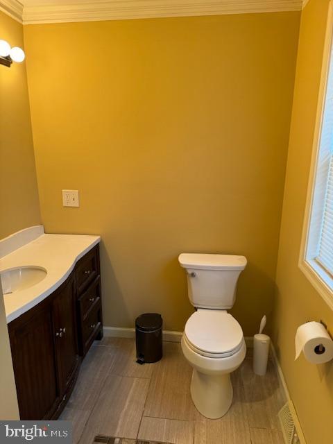 bathroom featuring hardwood / wood-style flooring, vanity, toilet, and crown molding