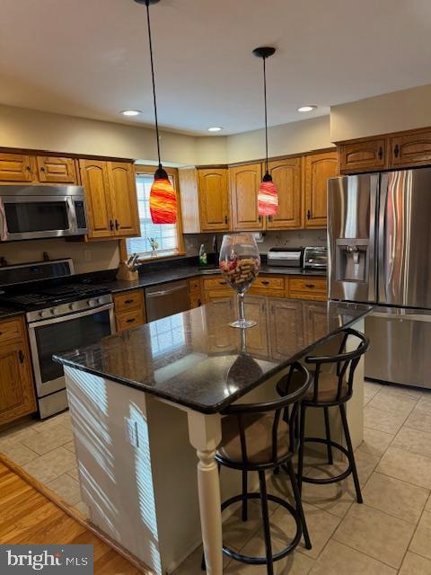 kitchen featuring a kitchen island, stainless steel appliances, and decorative light fixtures