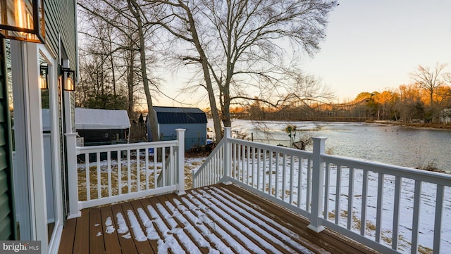 deck at dusk featuring a water view and a shed