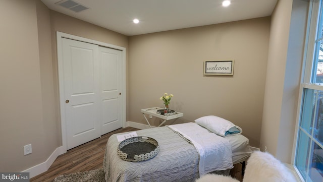 bedroom with dark hardwood / wood-style flooring and a closet