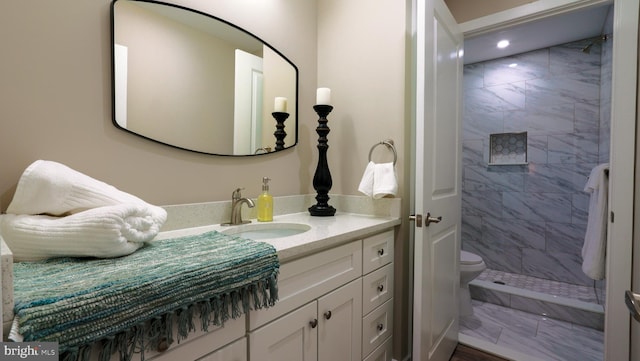 bathroom featuring tiled shower, vanity, and toilet