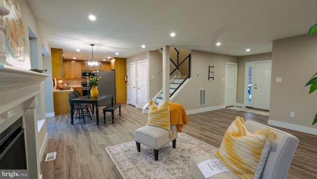 living room with light hardwood / wood-style flooring and a notable chandelier