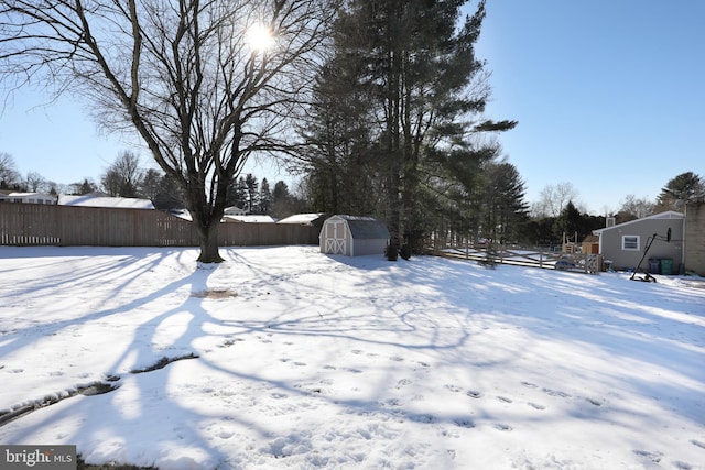 yard layered in snow featuring a storage shed