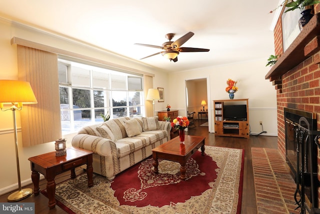 living room with a brick fireplace, ceiling fan, ornamental molding, and dark wood-type flooring