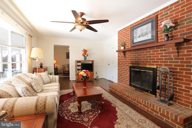 living room featuring ceiling fan, a brick fireplace, ornamental molding, and wood-type flooring