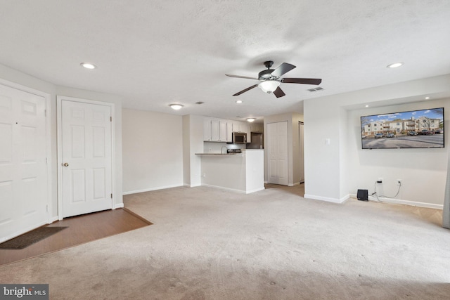 unfurnished living room featuring carpet, ceiling fan, and a textured ceiling