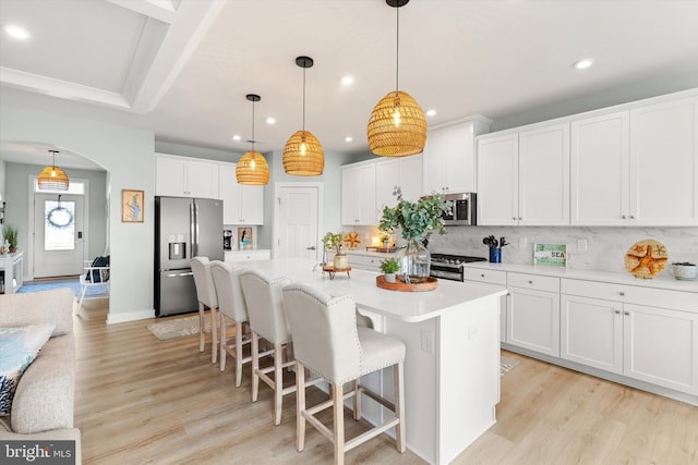 kitchen featuring appliances with stainless steel finishes, white cabinets, and decorative light fixtures