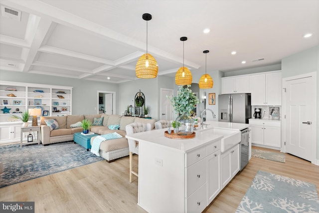 kitchen with hanging light fixtures, white cabinetry, appliances with stainless steel finishes, and a kitchen island with sink