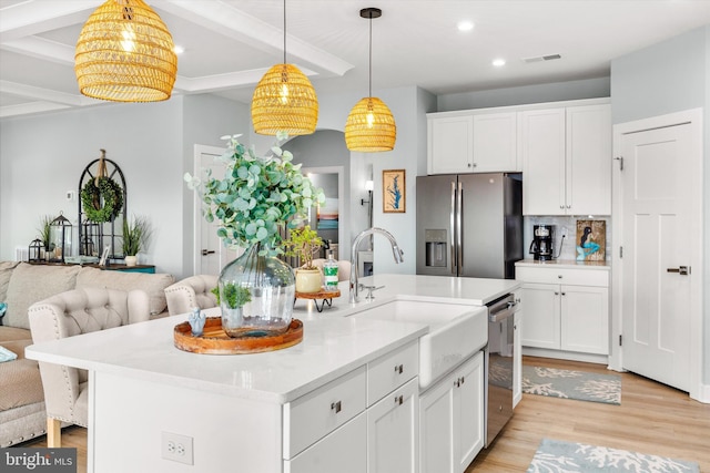 kitchen featuring light hardwood / wood-style flooring, stainless steel appliances, white cabinets, and a center island with sink