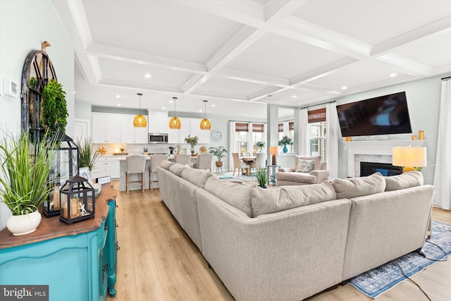 living room featuring coffered ceiling, beam ceiling, a fireplace, and light hardwood / wood-style floors