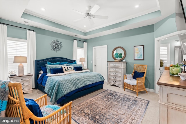 bedroom featuring multiple windows, light carpet, ceiling fan, and a tray ceiling