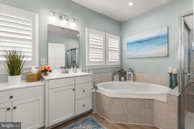 bathroom featuring hardwood / wood-style flooring, vanity, and shower with separate bathtub