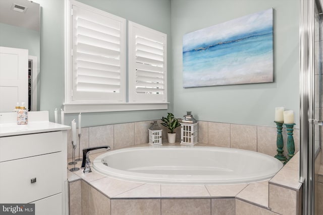 bathroom featuring a relaxing tiled tub and vanity