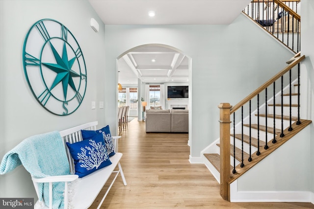 entryway with coffered ceiling, beam ceiling, and light wood-type flooring