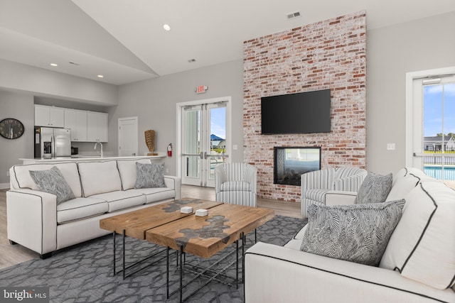 living room with a wealth of natural light, vaulted ceiling, hardwood / wood-style floors, and a fireplace