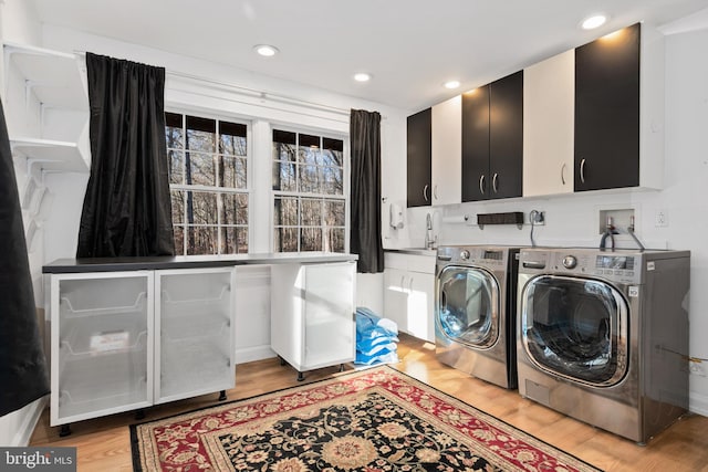 washroom featuring cabinets, independent washer and dryer, light wood-type flooring, and sink