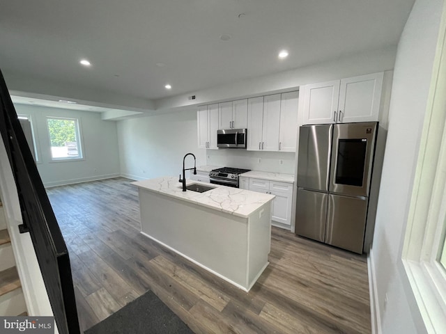 kitchen with white cabinets, stainless steel appliances, a kitchen island with sink, and sink