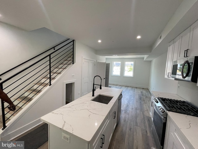 kitchen with white cabinets, appliances with stainless steel finishes, sink, and an island with sink