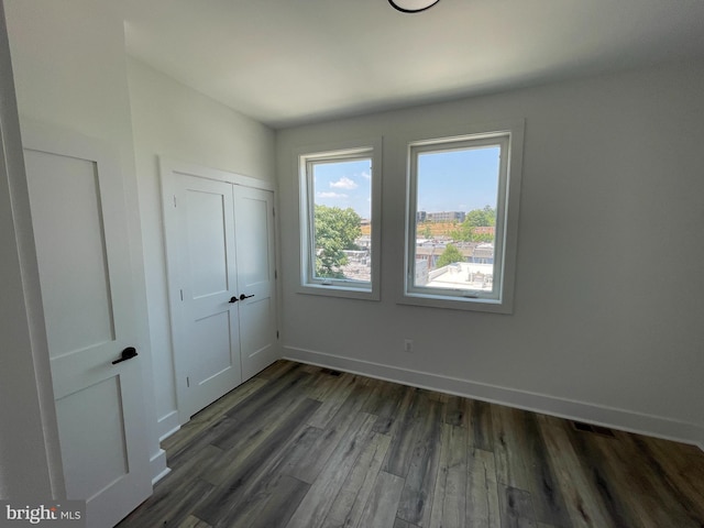 unfurnished bedroom with dark hardwood / wood-style flooring and a closet