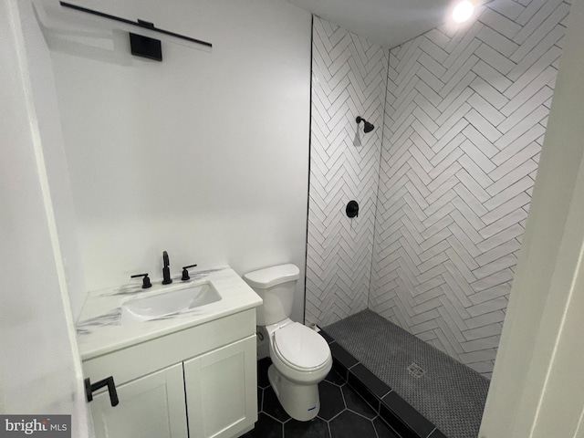 bathroom with tile patterned floors, vanity, toilet, and a tile shower