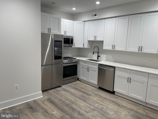 kitchen with white cabinetry, sink, stainless steel appliances, and light hardwood / wood-style flooring