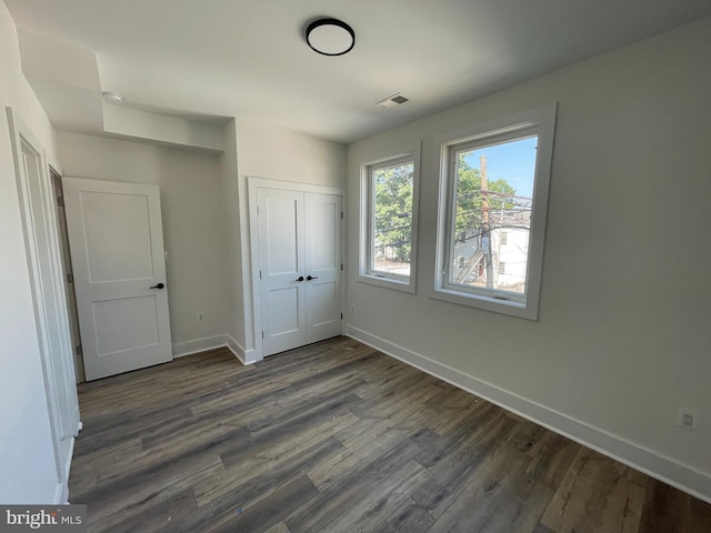 unfurnished bedroom with dark hardwood / wood-style floors and a closet