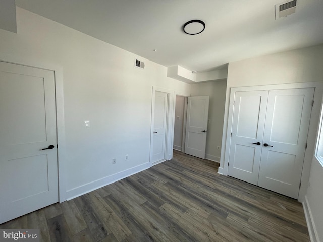 unfurnished bedroom with dark hardwood / wood-style flooring and a closet