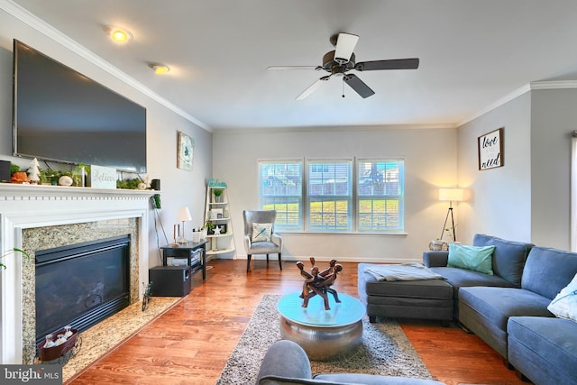 living room featuring a high end fireplace, wood-type flooring, ceiling fan, and ornamental molding