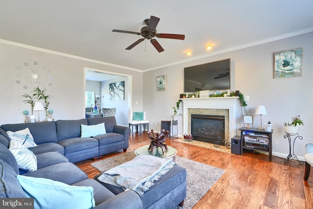 living room featuring hardwood / wood-style flooring, ceiling fan, ornamental molding, and a high end fireplace