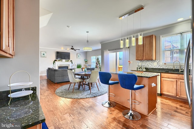 kitchen featuring a center island, dark stone counters, hanging light fixtures, and crown molding