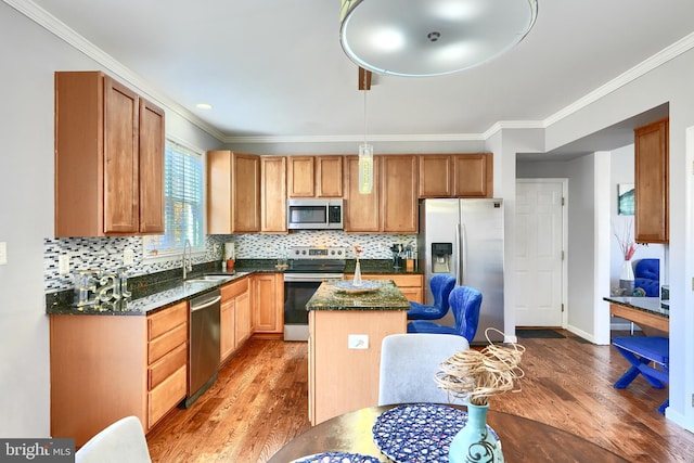 kitchen featuring a center island, sink, light wood-type flooring, ornamental molding, and appliances with stainless steel finishes