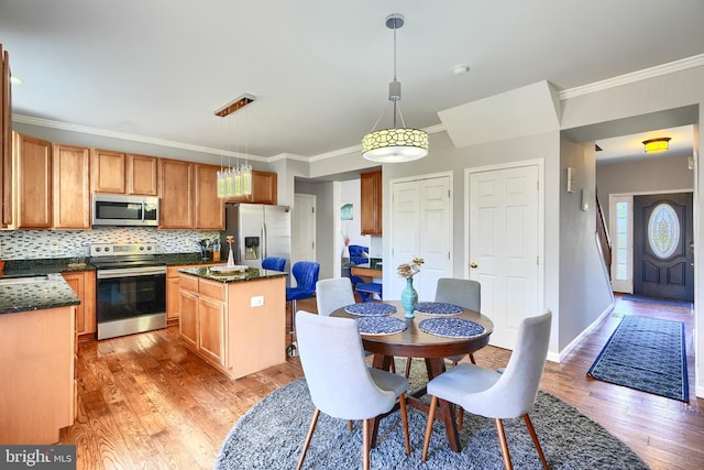 kitchen with a center island, tasteful backsplash, light hardwood / wood-style flooring, decorative light fixtures, and appliances with stainless steel finishes