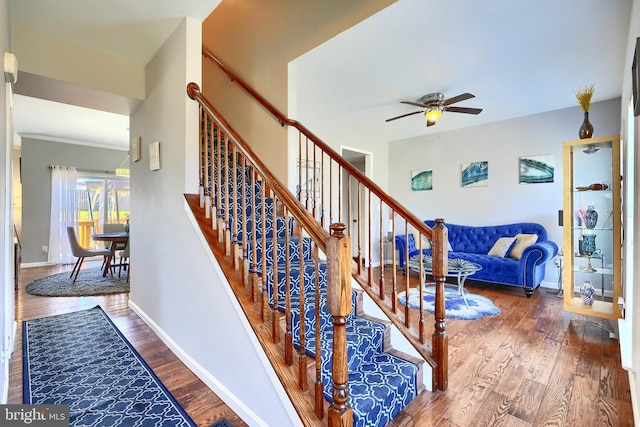 stairs featuring hardwood / wood-style flooring and ceiling fan