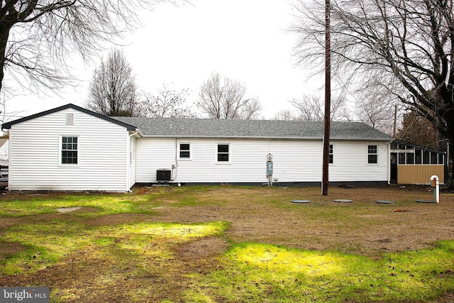 rear view of house with a sunroom, central AC unit, and a yard