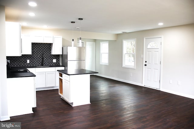 kitchen with a center island, dark wood-type flooring, sink, decorative light fixtures, and stainless steel refrigerator