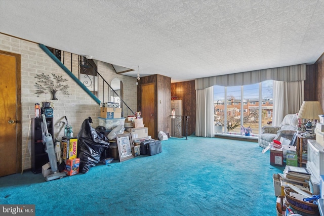 interior space with brick wall, carpet floors, a textured ceiling, and wooden walls