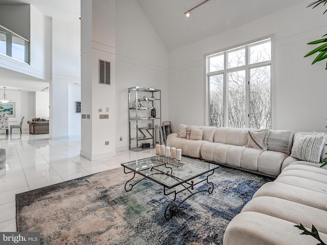 tiled living area with high vaulted ceiling, baseboards, and visible vents