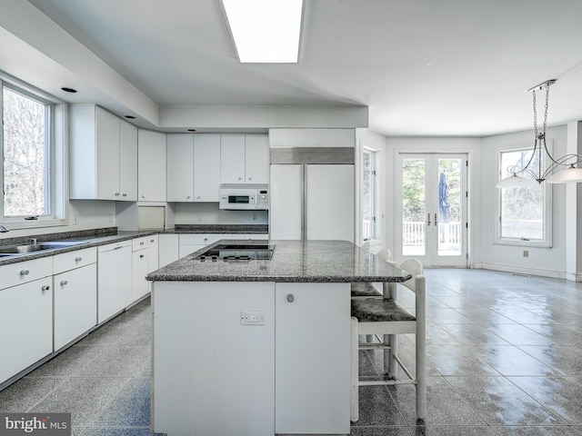 kitchen featuring a center island, french doors, white cabinetry, a sink, and white appliances