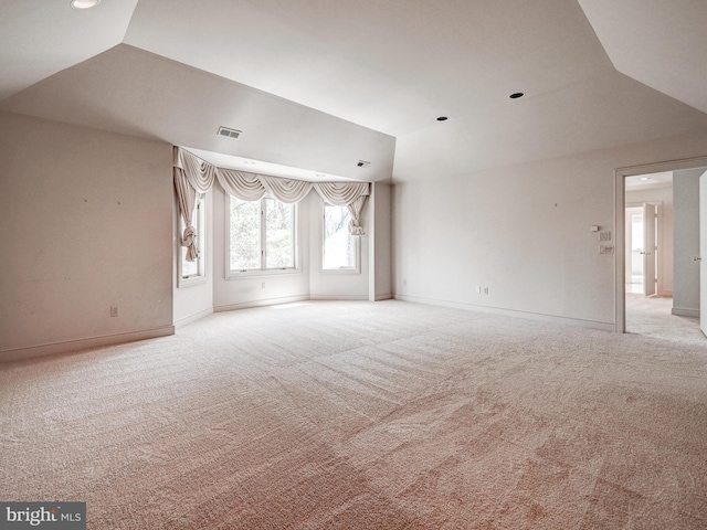 empty room featuring lofted ceiling, carpet flooring, visible vents, and baseboards