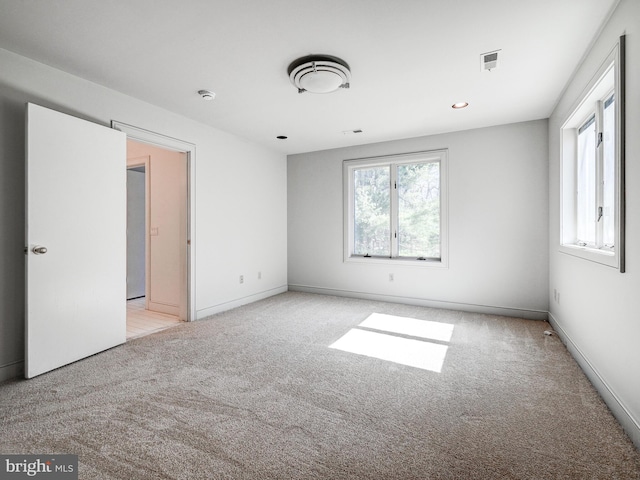 carpeted spare room featuring visible vents and baseboards