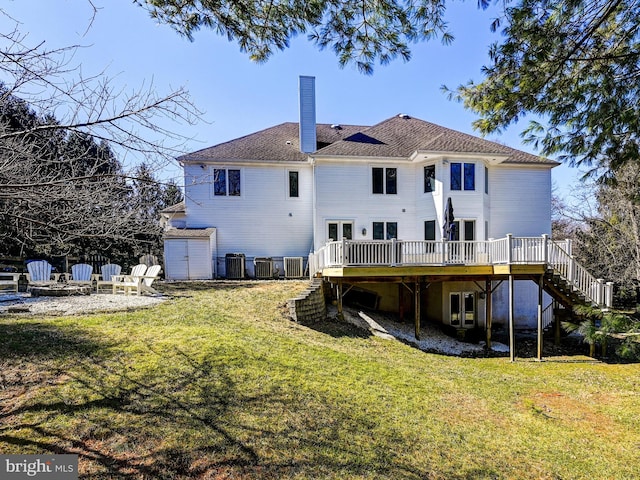 rear view of property with a deck, a yard, stairway, and a storage shed