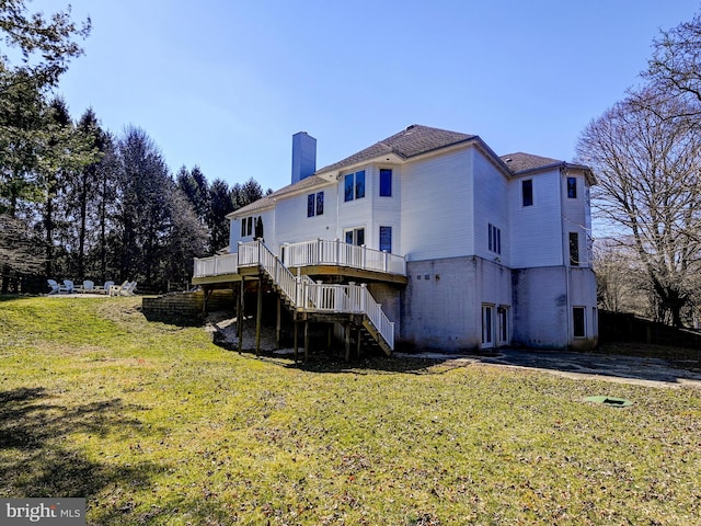 back of house featuring a deck, stairway, a chimney, and a lawn