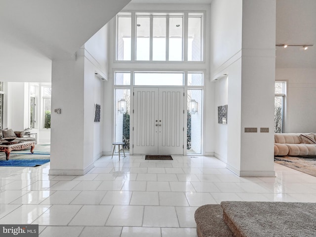 entryway featuring a high ceiling, baseboards, and light tile patterned flooring