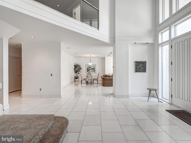 foyer entrance featuring a towering ceiling, light tile patterned floors, baseboards, and recessed lighting