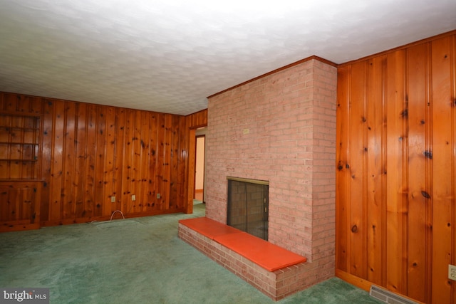 unfurnished living room with wood walls, carpet floors, and a brick fireplace