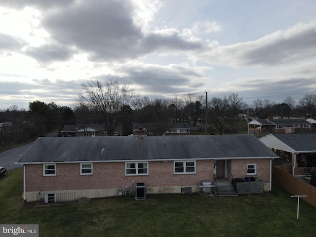 rear view of house featuring central air condition unit and a lawn