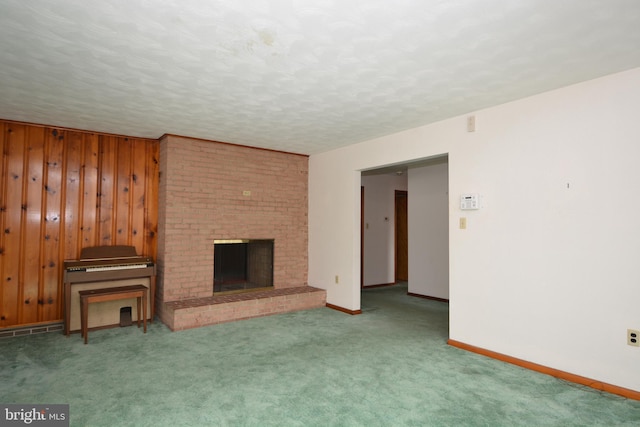 unfurnished living room with carpet, a fireplace, wooden walls, and a textured ceiling