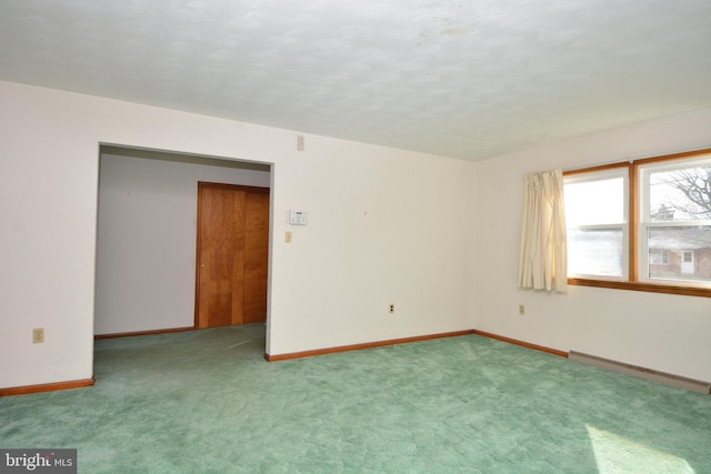 empty room with carpet flooring and a baseboard heating unit