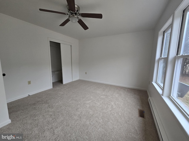 unfurnished bedroom with baseboard heating, ceiling fan, a closet, and carpet floors