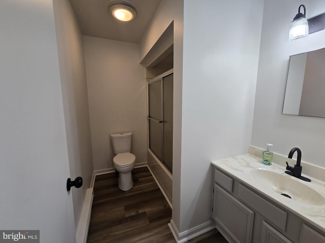 full bathroom with hardwood / wood-style floors, vanity, toilet, and bath / shower combo with glass door